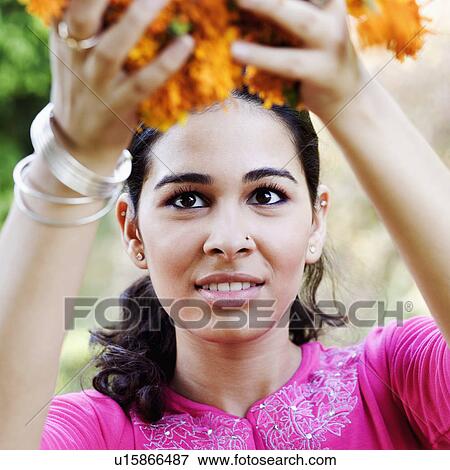 Stock Photo - Close-up of a young woman holding Marigolds. Fotosearch