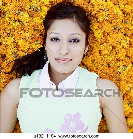 Picture - Portrait of a young woman lying on Marigolds. Fotosearch