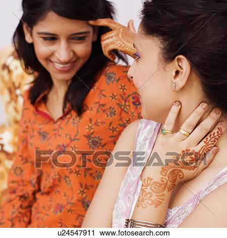 Stock Image - Young woman and a mid adult woman talking to each other. Fotosearch