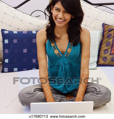 Young woman using a laptop on the bed View Large Photo Image Stock Image - Young woman using a laptop on the bed. Fotosearch