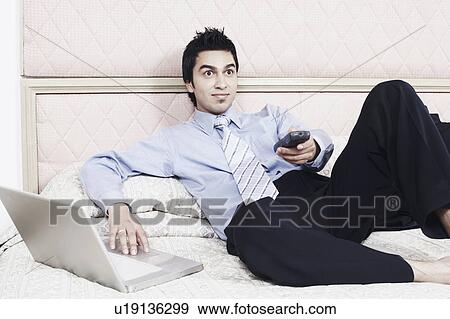Stock Photo - Businessman holding a remote control with his eyes wide open. Fotosearch