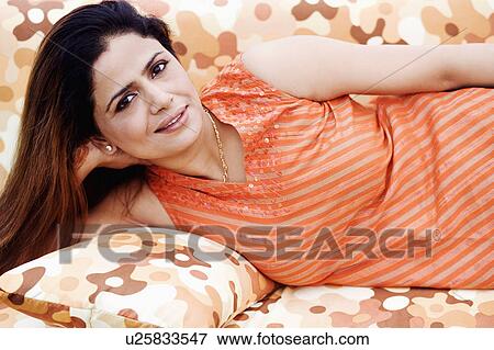 Portrait of a mid adult woman lying on a couch and smiling View Large Photo Image Stock Photo - Portrait of a mid adult woman lying on a couch and smiling. Fotosearch