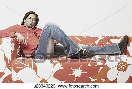 Stock Image - Portrait of a young man listening to an MP3 player. Fotosearch