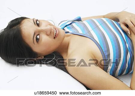 Stock Image - Portrait of a young woman lying on her back and smiling. Fotosearch