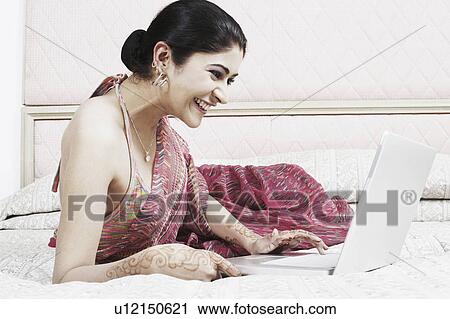 Stock Image - Side profile of a young woman using a laptop. Fotosearch