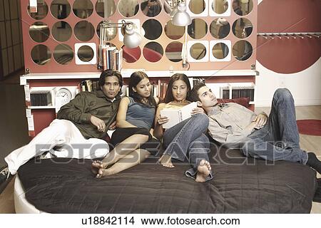 Picture - Two young couples lying on the bed. Fotosearch