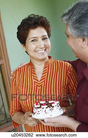 Stock Image - Close-up of a mature couple holding a birthday cake. Fotosearch