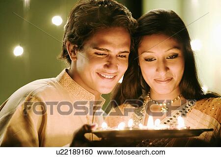 Close-up of a young couple holding oil lamps in a plate View Large Photo Image Stock Image - Close-up of a young couple holding oil lamps in a plate. Fotosearch