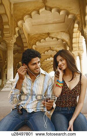 Close-up of a young couple listening to music on headphones, Agra Fort, Agra, Uttar Pradesh, India View Large Photo Image Stock Image - Close-up of a young couple listening to music on headphones, Agra Fort, Agra, Uttar Pradesh, India. Fotosearch