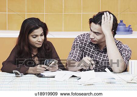 Close-up of a young couple looking at credit cards View Large Photo Image Stock Photo - Close-up of a young couple looking at credit cards. Fotosearch
