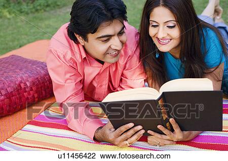 Close-up of a young couple lying on a picnic blanket and reading a book View Large Photo Image Stock Image - Close-up of a young couple lying on a picnic blanket and reading a book. Fotosearch