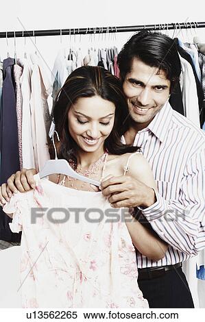 Stock Photography - Close-up of a young couple standing in a clothing store. Fotosearch