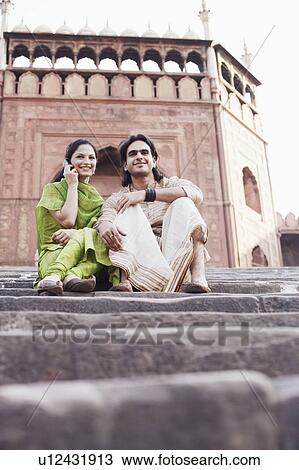 Low angle view of a young couple sitting on the steps in front of a building, Jama Masjid, Delhi, India View Large Photo Image Stock Image - Low angle view of a young couple sitting on the steps in front of a building, Jama Masjid, Delhi, India. Fotosearch