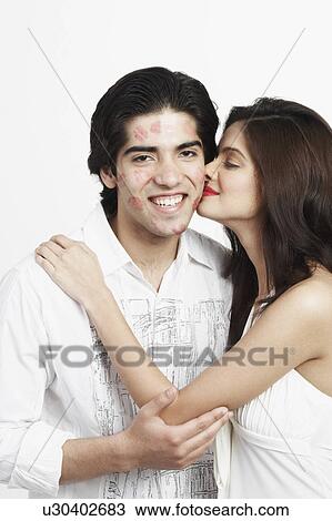 Stock Image - Side profile of a young woman kissing a young man. Fotosearch