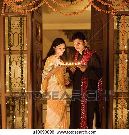 Young couple holding oil lamps in a plate View Large Photo Image Stock Photo - Young couple holding oil lamps in a plate. Fotosearch