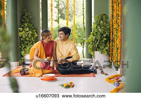 Stock Image - Young couple sitting on a mat and smiling. Fotosearch