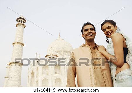 Stock Photo - Young couple standing in front of a mausoleum, Taj Mahal, Agra, Uttar Pradesh, India. Fotosearch
