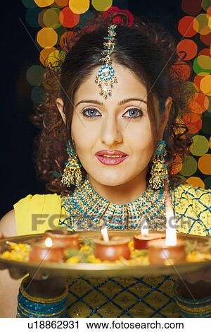 Stock Image - Portrait of a young woman holding a plate of religious offerings. Fotosearch