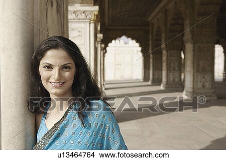 Portrait of a young woman leaning against a wall and smiling View Large Photo Image Picture - Portrait of a young woman leaning against a wall and smiling. Fotosearch