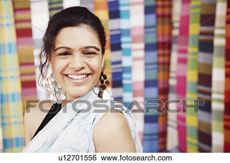 Stock Photograph - Portrait of a young woman smiling in a clothing store. Fotosearch