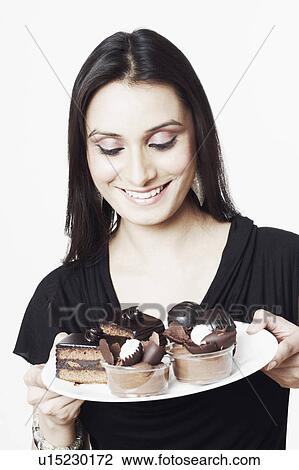Stock Image - Close-up of a young woman holding a plate of pastry and chocolate ice-cream. Fotosearch