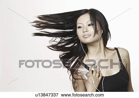 Stock Photo - Close-up of a young woman listening to an MP3 player. Fotosearch