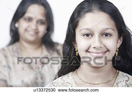 Portrait of a girl smiling with her mother standing behind her View Large Photo Image Stock Image - Portrait of a girl smiling with her mother standing behind her. Fotosearch