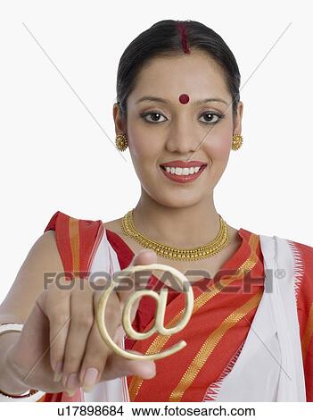 Picture - Portrait of a young woman holding an At symbol and smiling. Fotosearch