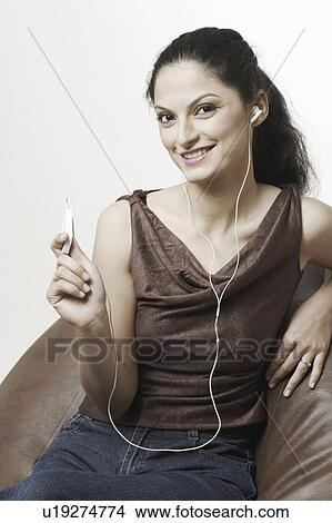 Picture - Portrait of a young woman listening to an MP3 player. Fotosearch