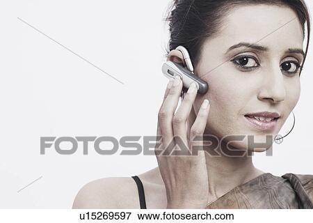 Stock Photo - Portrait of a young woman wearing a hands free device. Fotosearch