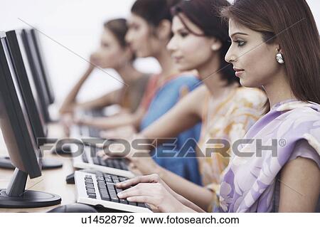Stock Image - Side profile of a businesswoman sitting in front of a computer. Fotosearch