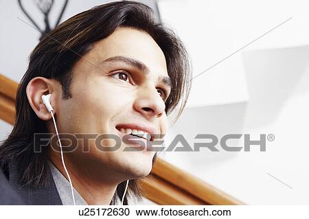 Stock Image - Close-up of a businessman wearing headphones and listening to music. Fotosearch