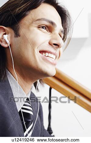 Close-up of a businessman wearing headphones and listening to music View Large Photo Image Stock Photograph - Close-up of a businessman wearing headphones and listening to music. Fotosearch