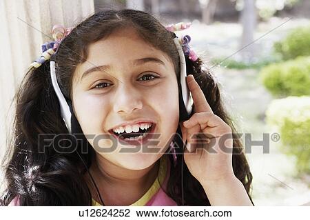 Stock Image - Close-up of a girl wearing headphones and listening to music. Fotosearch