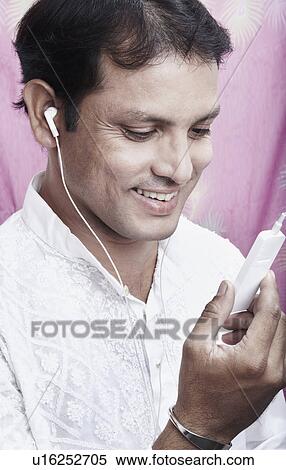 Stock Photography - Close-up of a mid adult man listening to an MP3 player. Fotosearch