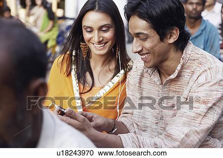 Stock Image - Close-up of a young couple sitting on a rickshaw listening to an MP3 player. Fotosearch