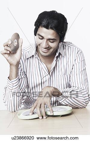 Stock Image - Close-up of a young man listening to music and holding a CD. Fotosearch