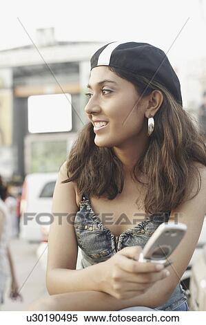 Close-up of a young woman holding a mobile phone View Large Photo Image Stock Photography - Close-up of a young woman holding a mobile phone. Fotosearch