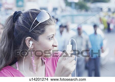 Close-up of a young woman listening to an MP3 player View Large Photo Image Picture - Close-up of a young woman listening to an MP3 player. Fotosearch