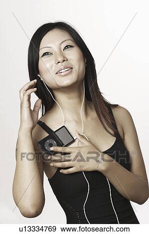 Stock Photo - Close-up of a young woman listening to an MP3 player. Fotosearch