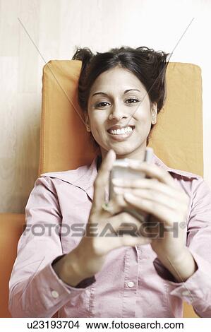 High angle view of a young woman holding a mobile phone View Large Photo Image Picture - High angle view of a young woman holding a mobile phone. Fotosearch