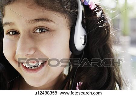 Stock Photo - Portrait of a girl listening to music on a pair of headphones. Fotosearch