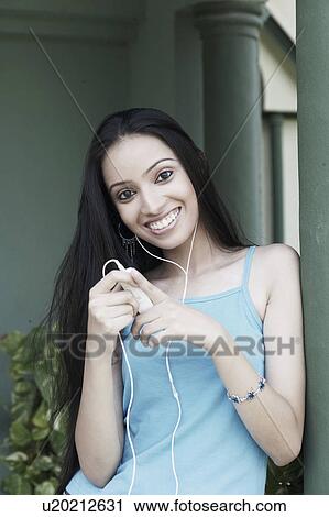Stock Image - Portrait of a teenage girl listening to an MP3 player. Fotosearch