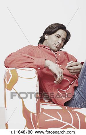 Stock Image - Portrait of a young man listening to an MP3 player. Fotosearch