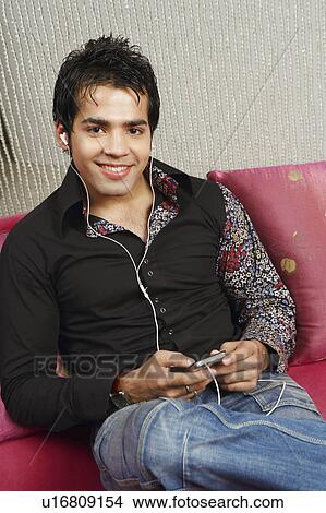 Picture - Portrait of a young man listening to music on an MP3 player. Fotosearch
