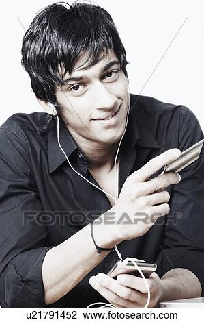 Portrait of a young man listening to music and holding a credit card View Large Photo Image Stock Image - Portrait of a young man listening to music and holding a credit card. Fotosearch