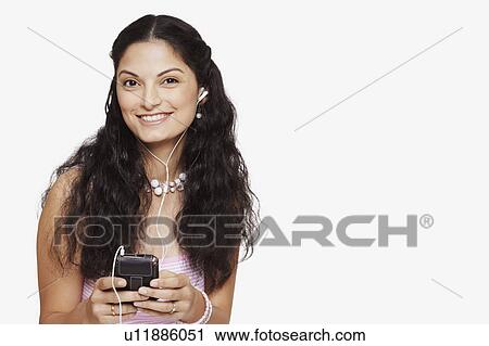 Stock Image - Portrait of a young woman listening to an MP3 player. Fotosearch