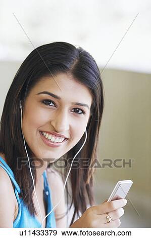 Stock Photo - Portrait of a young woman listening to an MP3 player. Fotosearch