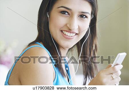 Stock Photo - Portrait of a young woman listening to an MP3 player. Fotosearch