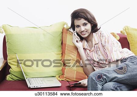 Picture - Portrait of a young woman talking on a mobile phone. Fotosearch